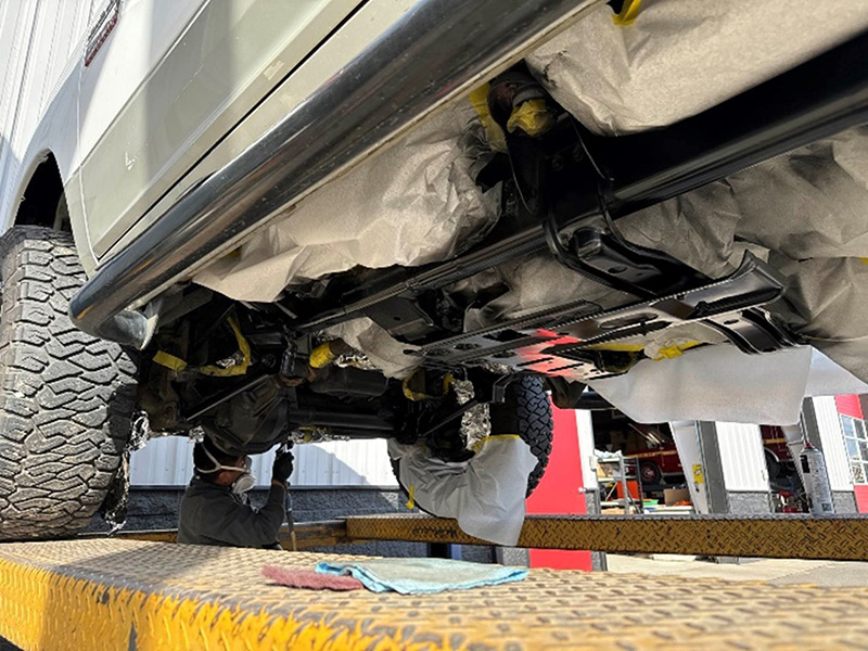 Mechanic looking underneath vehicle with a flashlight